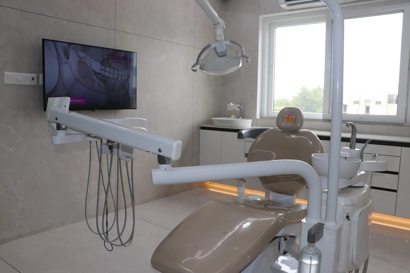A treatment room with a wall monitor at Leela Super Speciality Dental Hospital.
